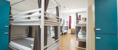 A dormitory room with bunk beds, a desk, and a chair.