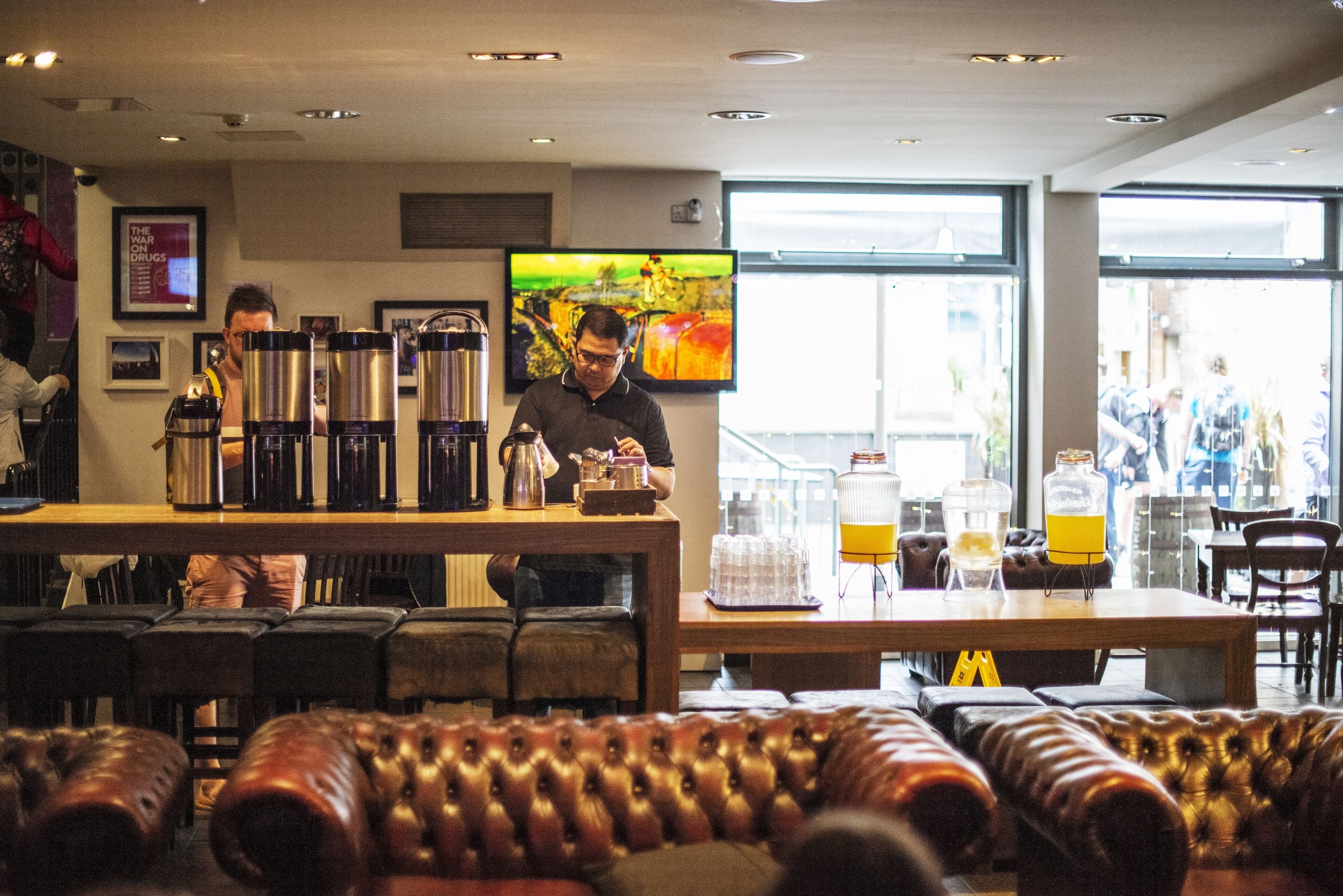 A bar area with a counter, coffee machines, and seating.