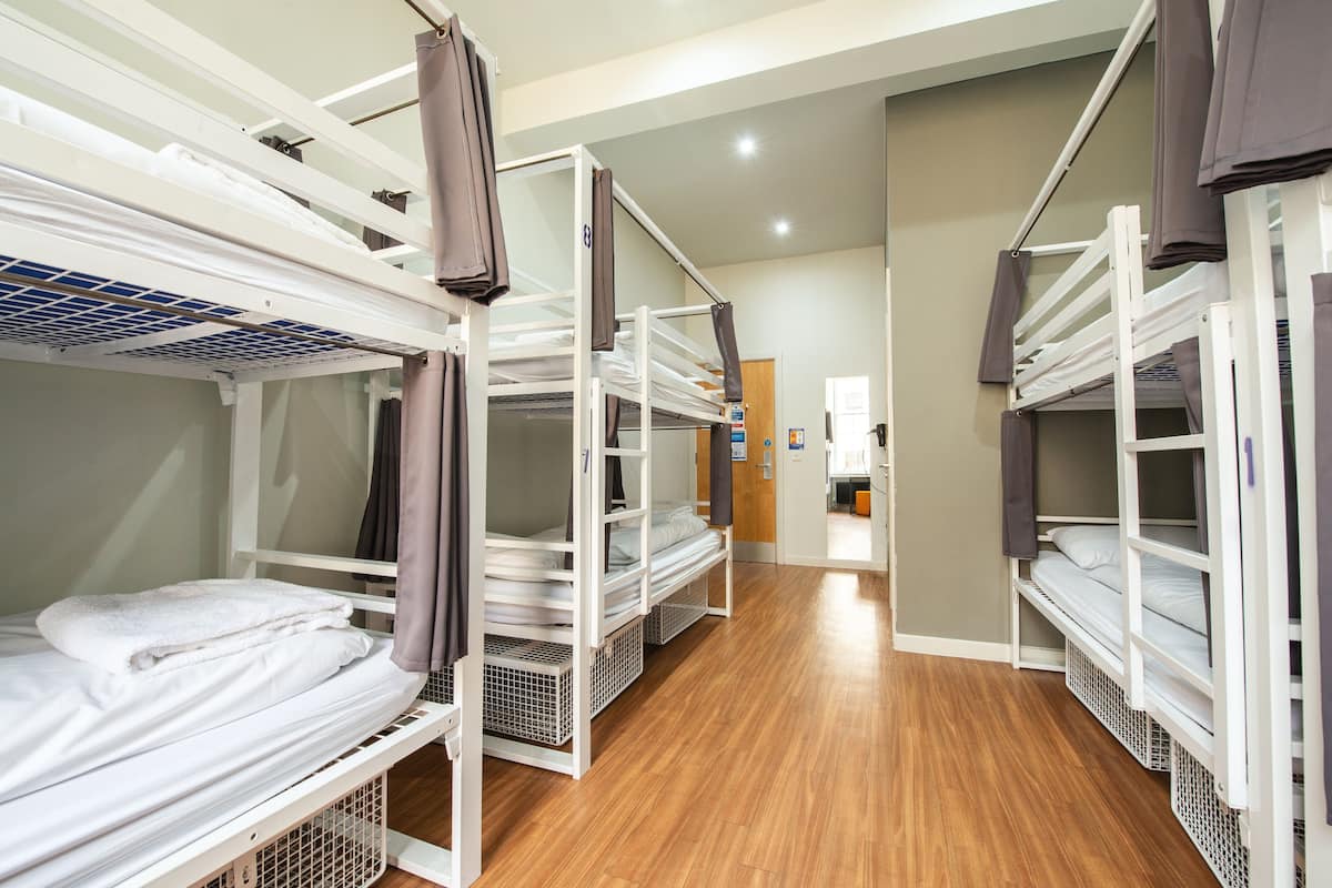 A corridor with bunk beds, wooden flooring, and a door at the end.