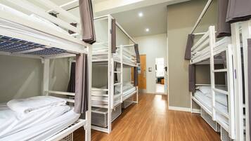 A corridor with bunk beds, wooden flooring, and a door at the end.