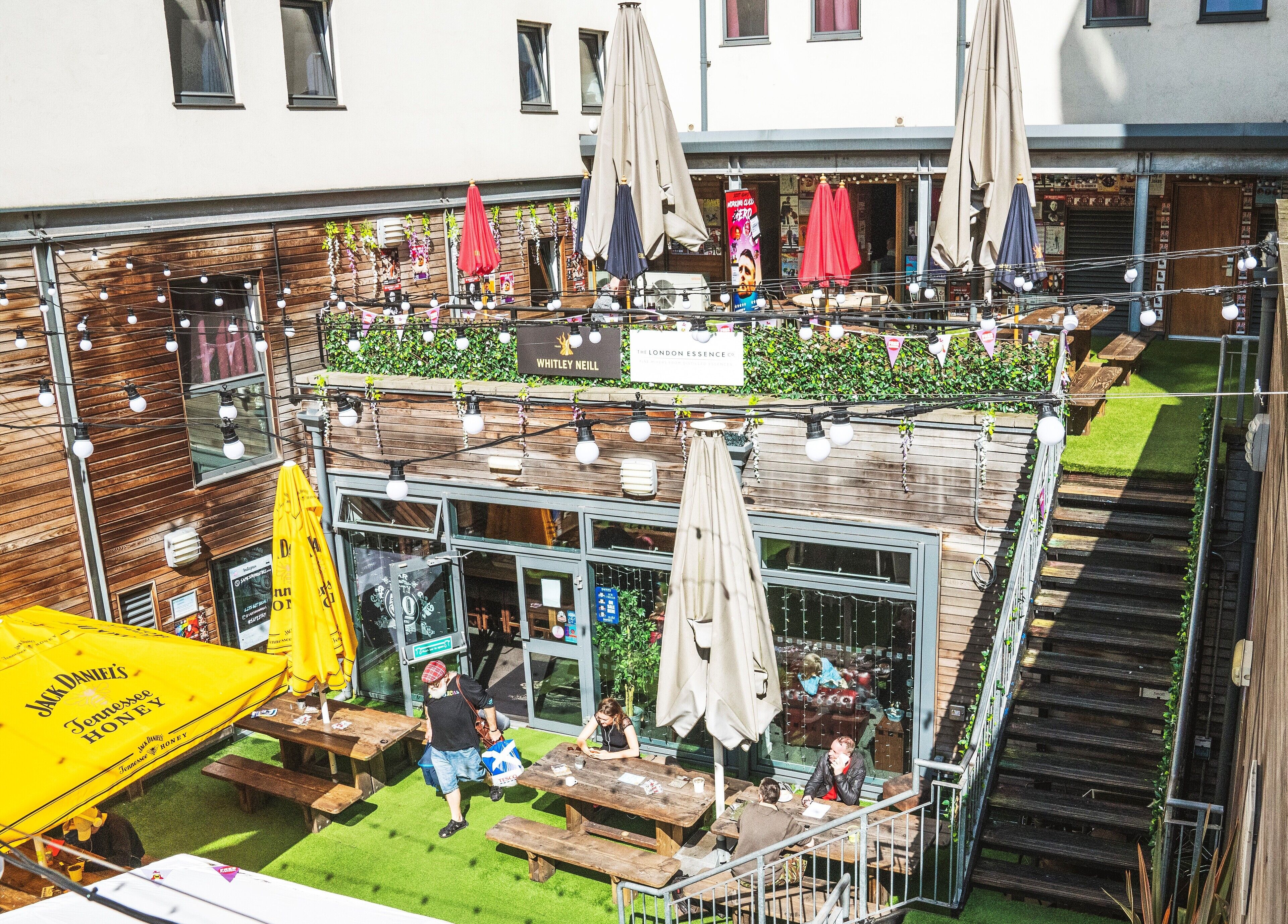 A rooftop bar with outdoor seating, string lights, and umbrellas.