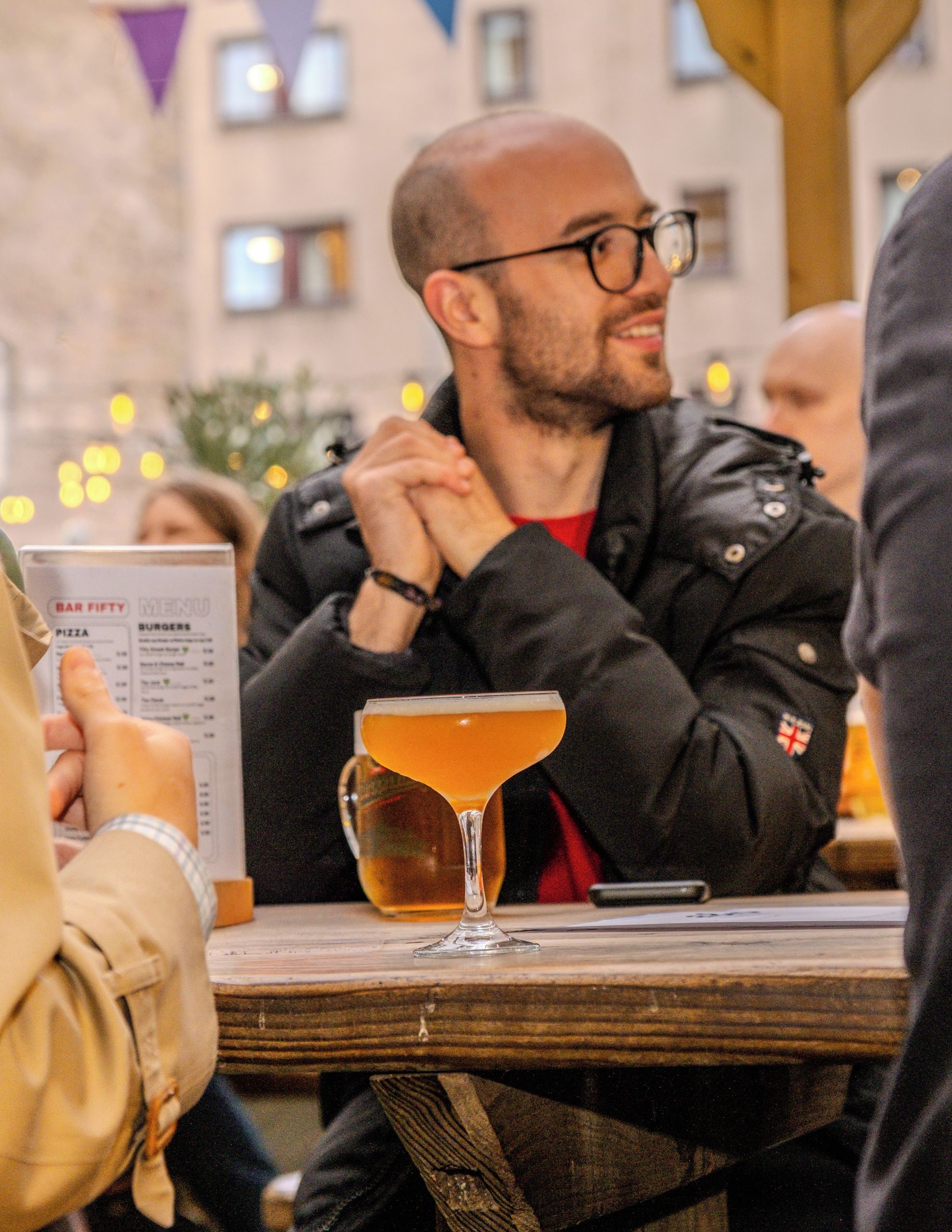 Una persona sentada a una mesa con un menú y una jarra de cerveza.