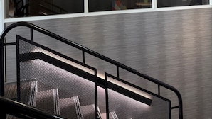 Un interior moderno con una lámpara colgante única, una escalera y vistas al exterior.