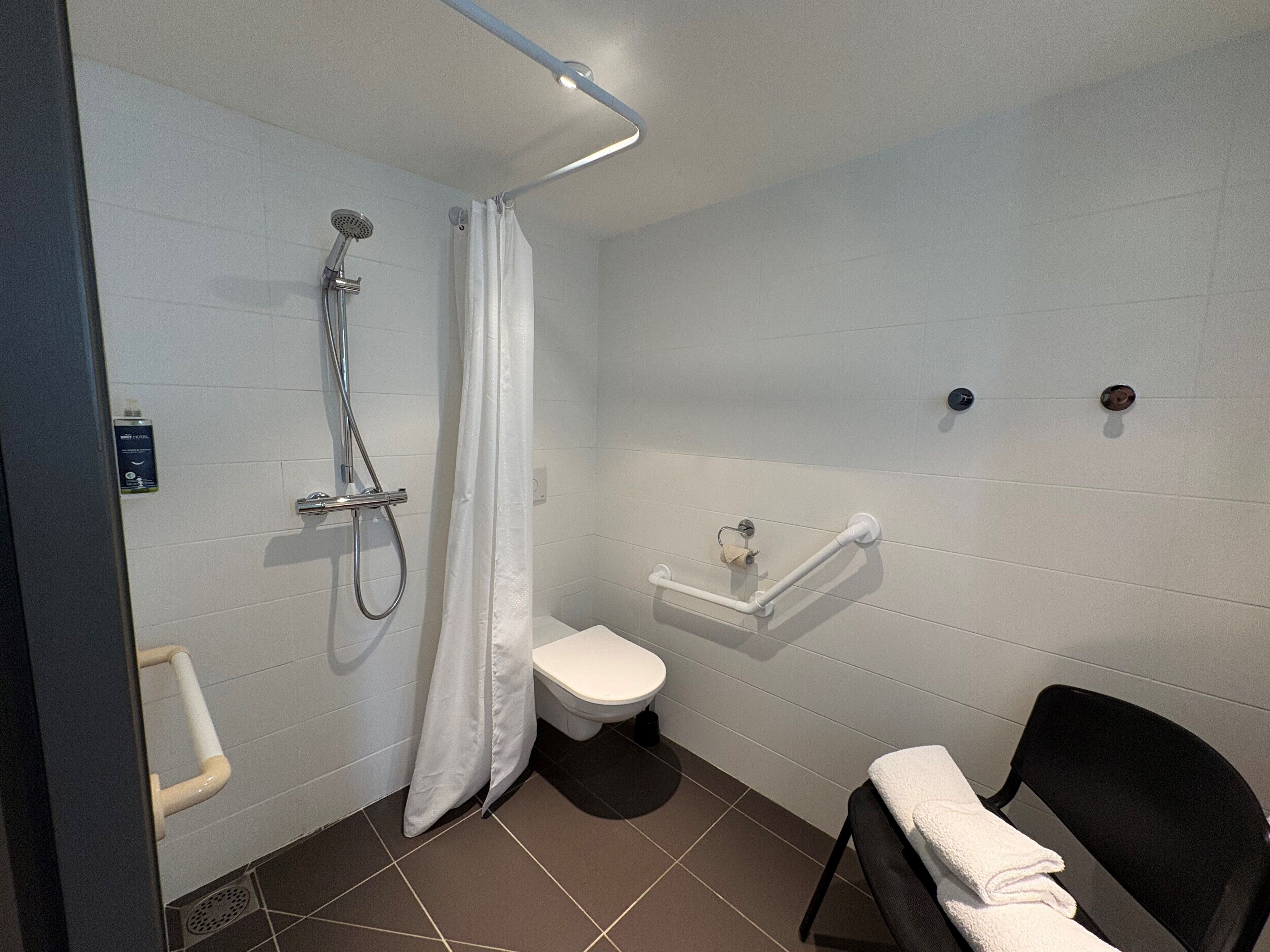 A modern bathroom with a shower, toilet, and a towel rack.