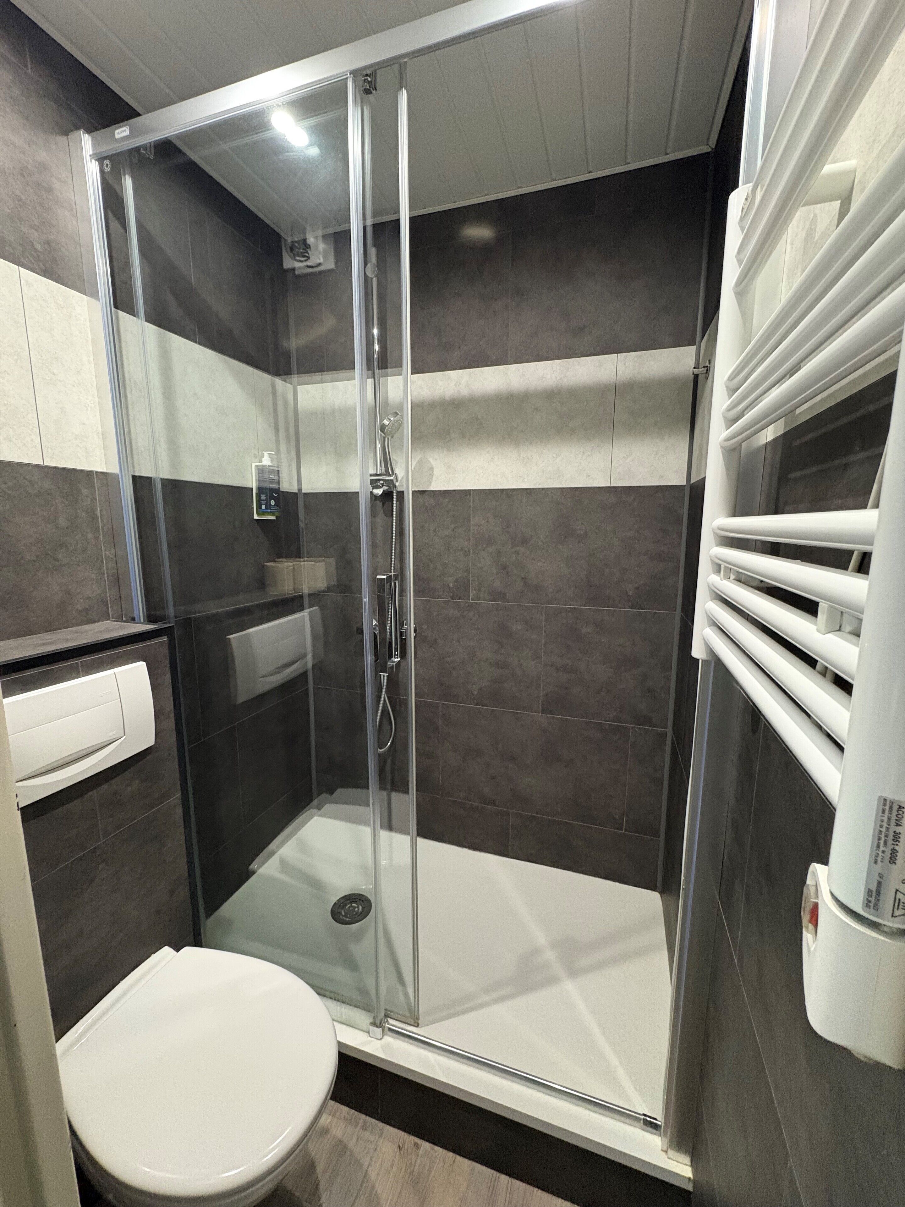 Un baño moderno con ducha de vidrio, inodoro y toallero.