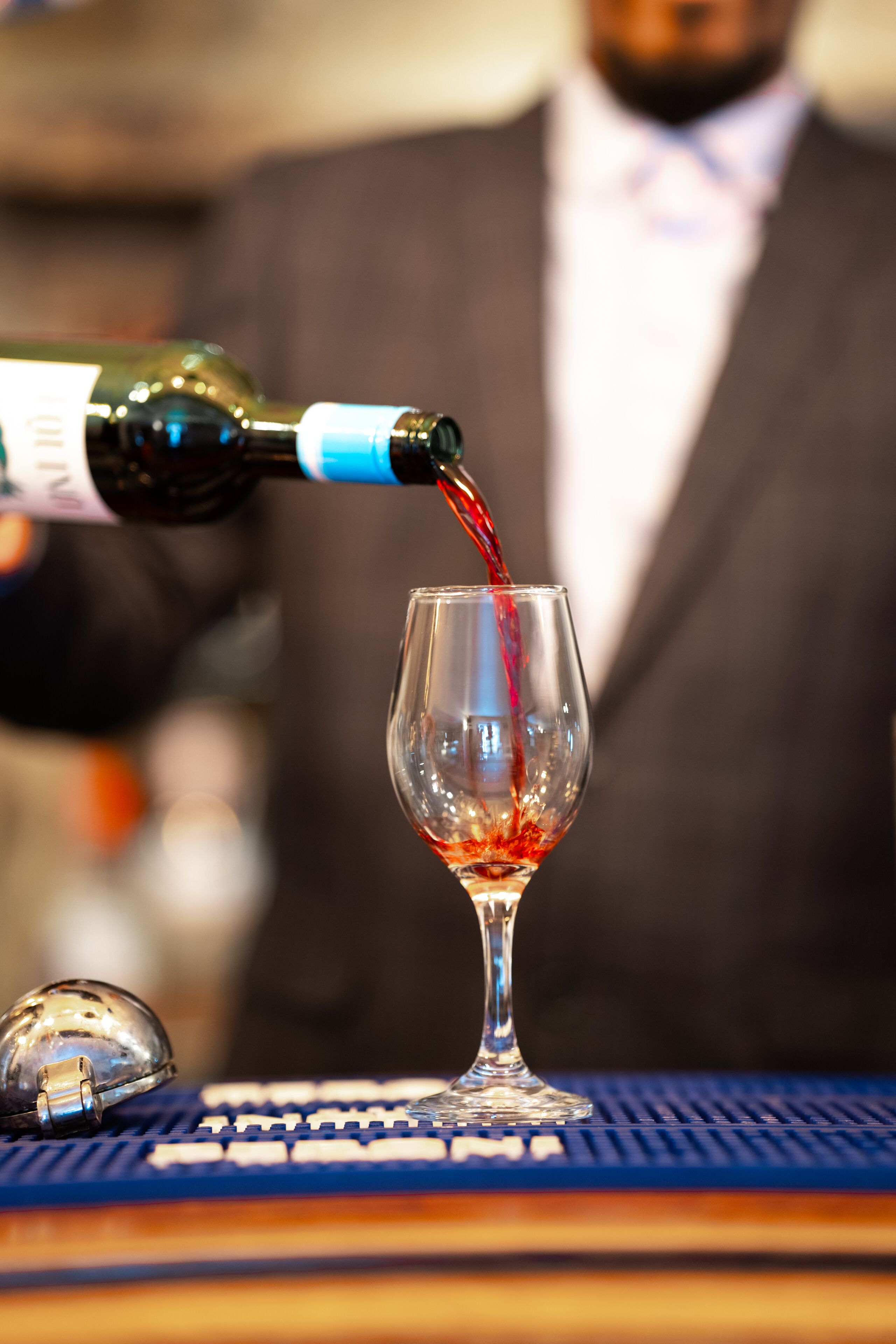 Ein Weinglas wird an einer Bar mit Rotwein gefüllt.