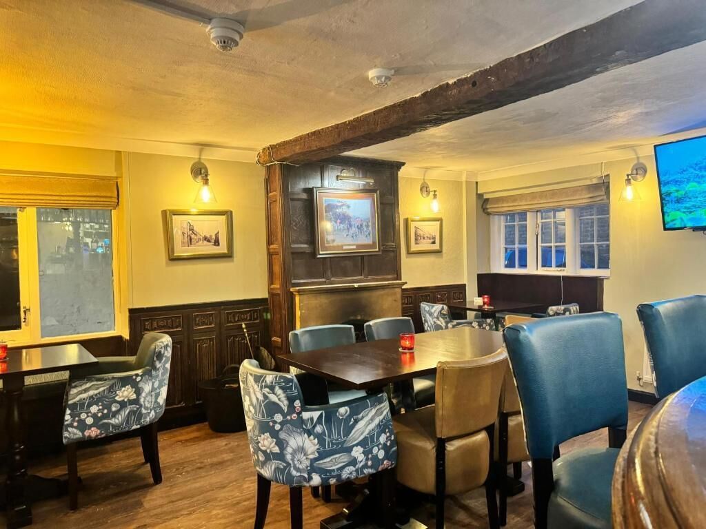 A dining area with wooden tables and chairs, framed pictures on the walls, and a television mounted on the wall.