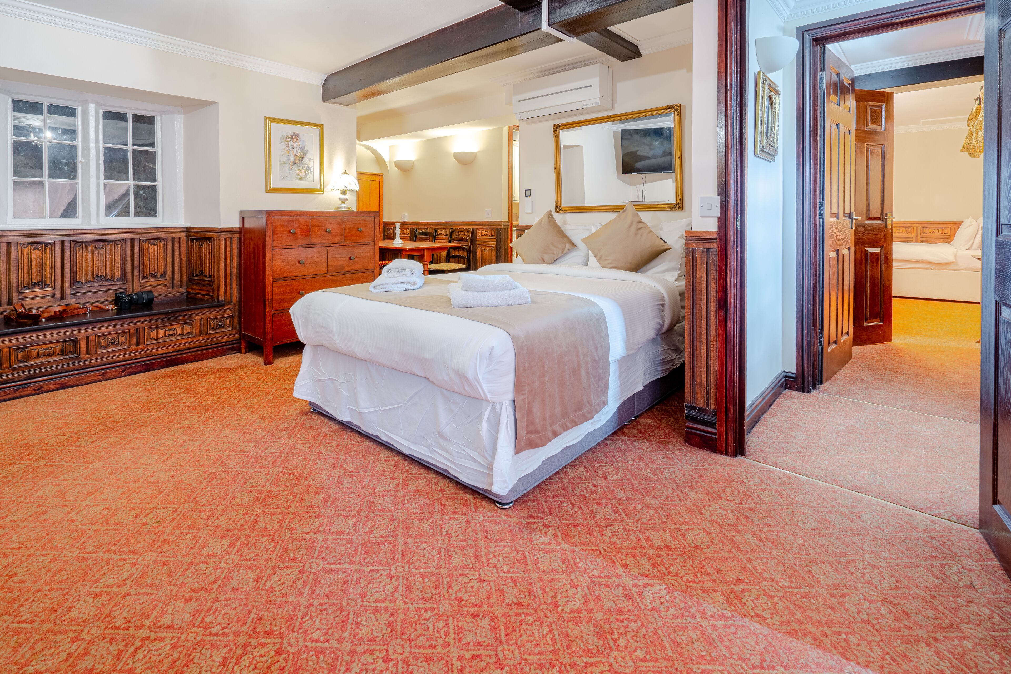 Een hotelkamer met een groot bed, een houten dressoir, een bureau en een stoel.