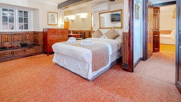Een hotelkamer met een groot bed, een houten dressoir, een bureau en een stoel.