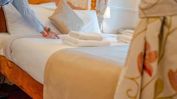 A neatly made bed with white linens and folded towels.