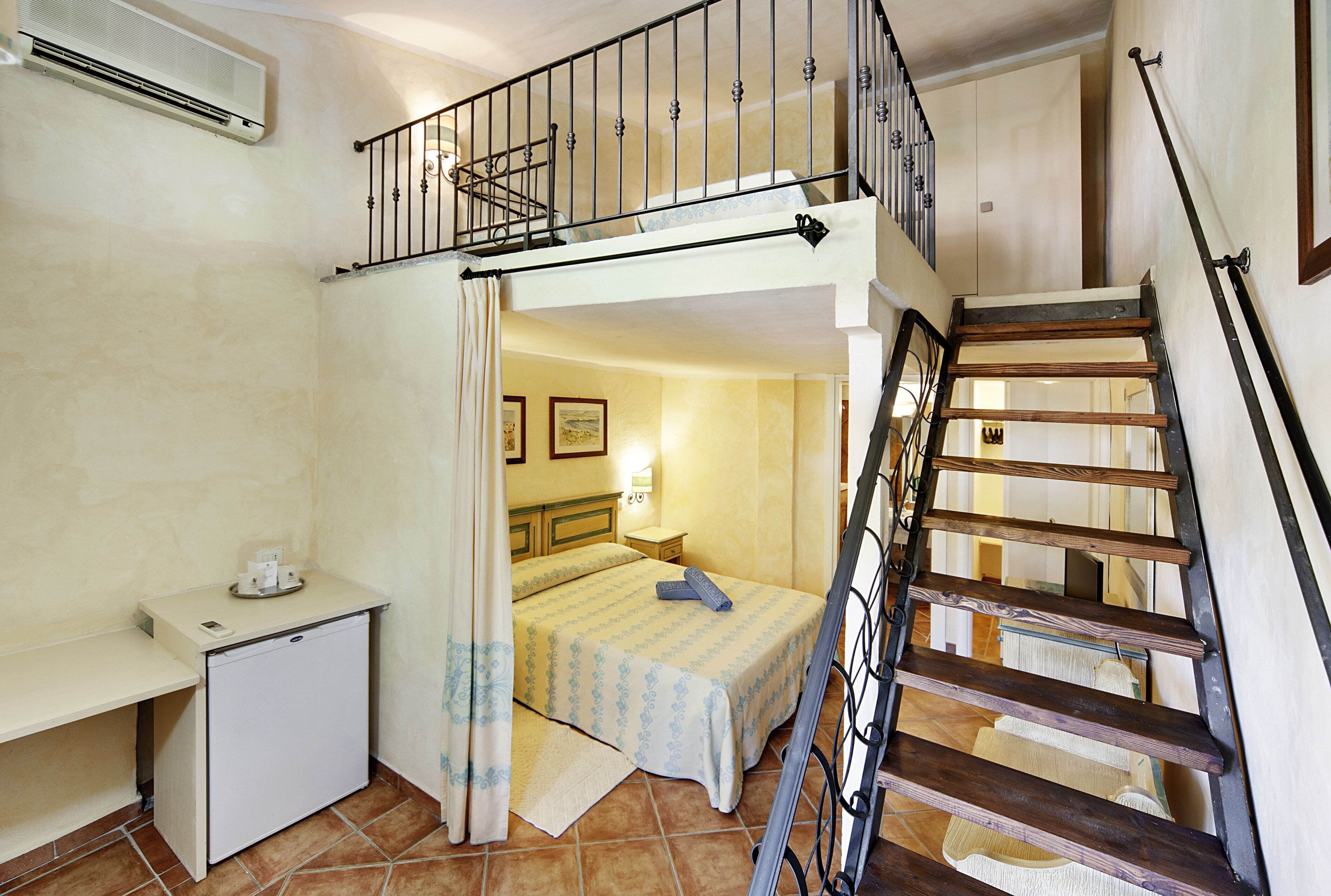 Habitación compacta con literas, un escritorio pequeño y una escalera.
