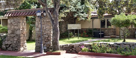 A stone entrance with a sign for the Colonna del Golf Resort & Residence Reception.