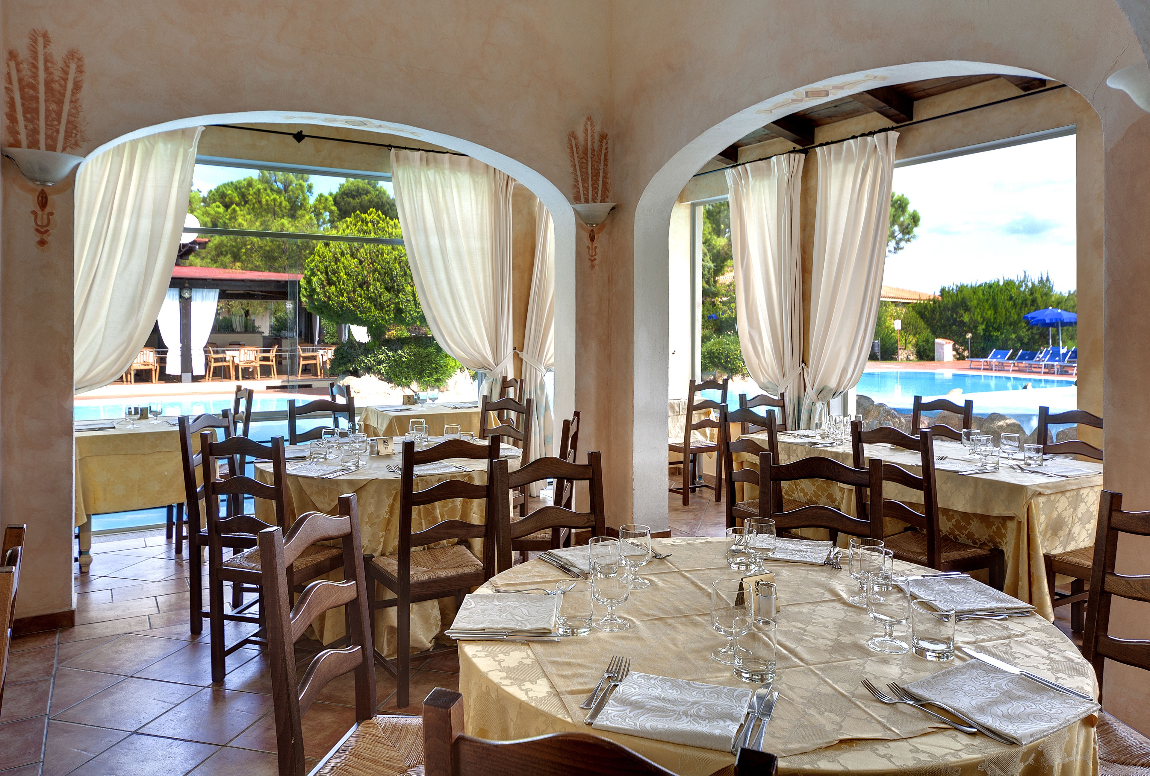 A restaurant with round tables, chairs, and a view of a pool.