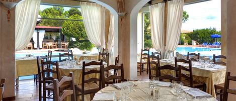 A restaurant with round tables, chairs, and a view of a pool.