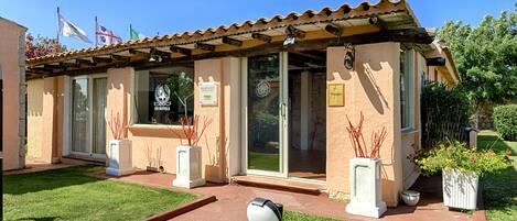 A hotel with a tiled roof, large glass doors, and a well-maintained lawn.