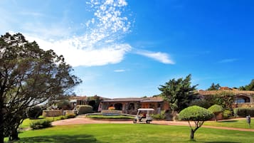 A golf course with a clubhouse, well-maintained lawns, and a clear blue sky.