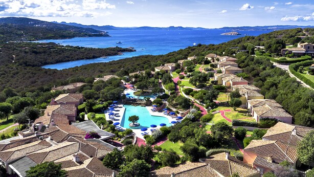 Ein Resort mit Swimmingpool, terrassenförmig angelegten Häusern und Meerblick.