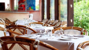 Ein Restaurant mit Korbstühlen und weißen Tischdecken, eingerichtet für das Essen.