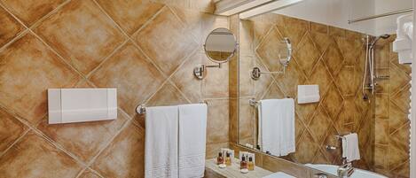 Une salle de bain avec un grand miroir, un lavabo et une douche.