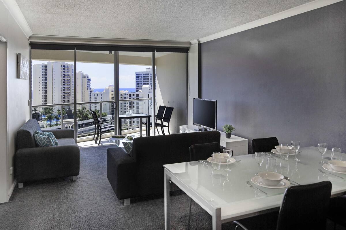 A modern living room with a balcony, a dining area, and a TV.