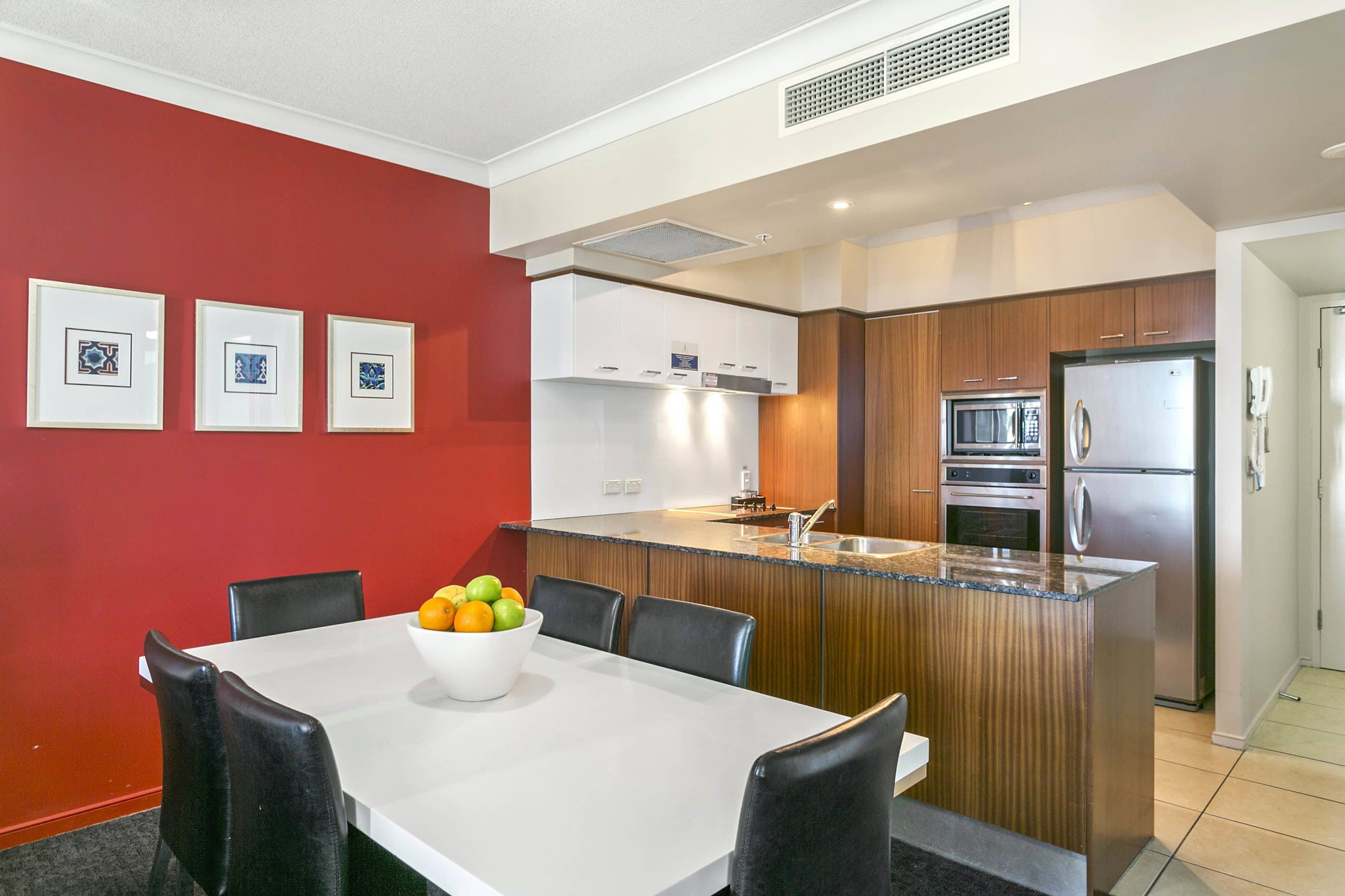 A modern kitchen with a central island, white cabinetry, and stainless steel appliances.