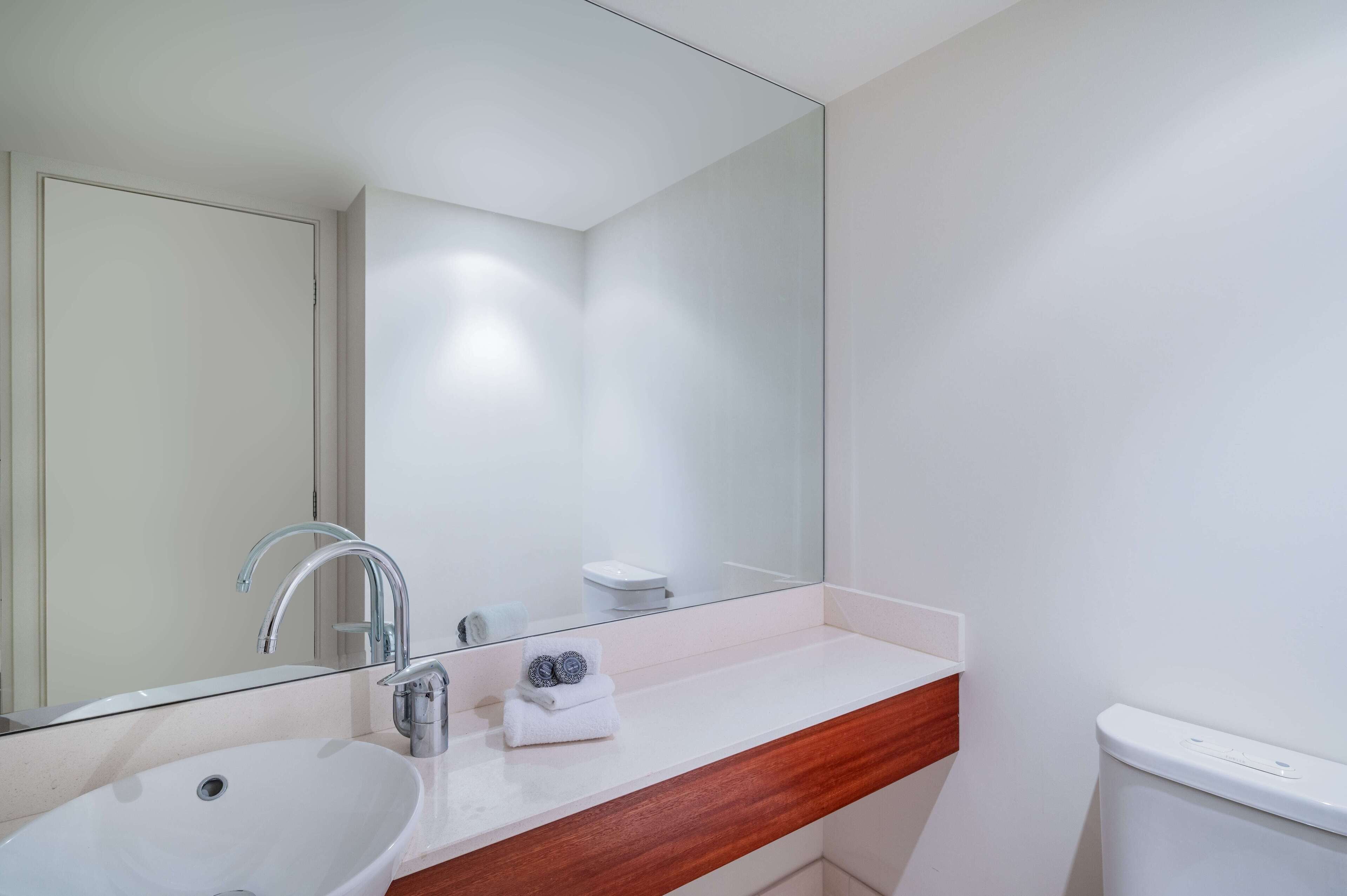 Une salle de bain moderne avec un lavabo blanc, un miroir et des toilettes.