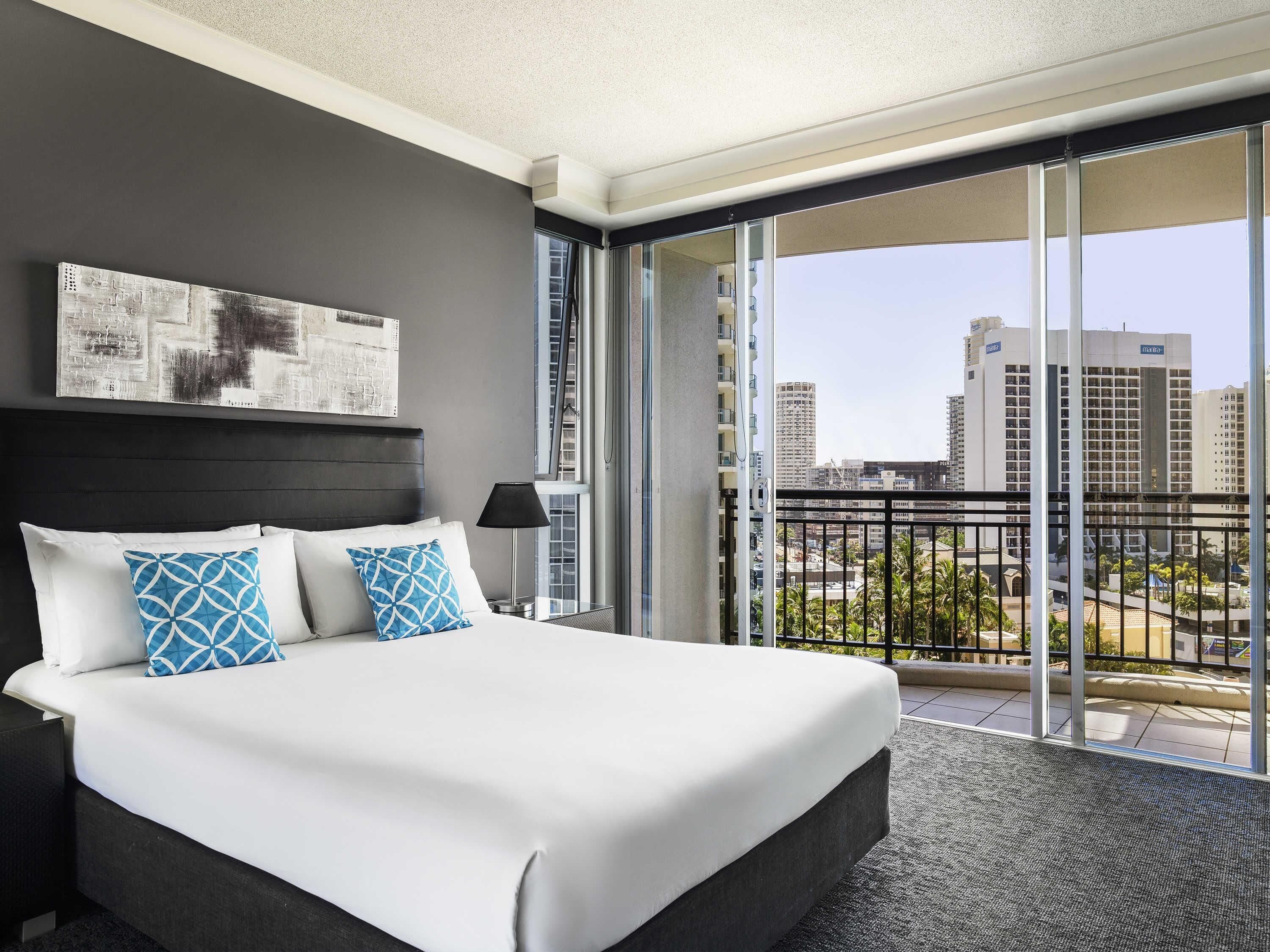 Une chambre d’hôtel dotée d’un grand lit, d’un balcon offrant une vue sur la ville et d’un design moderne.