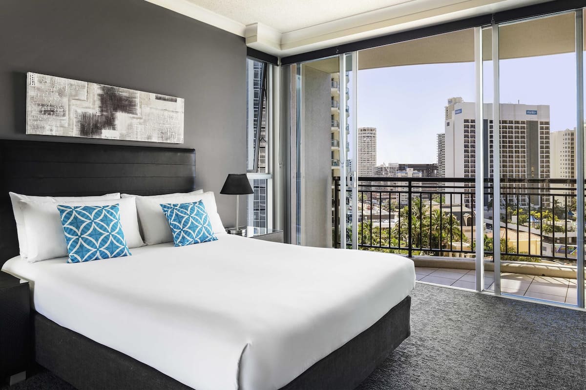 A hotel room with a large bed, a city view balcony, and a modern design.