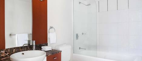 A modern bathroom with a large mirror, a marble countertop sink, a toilet, and a glass-enclosed shower.