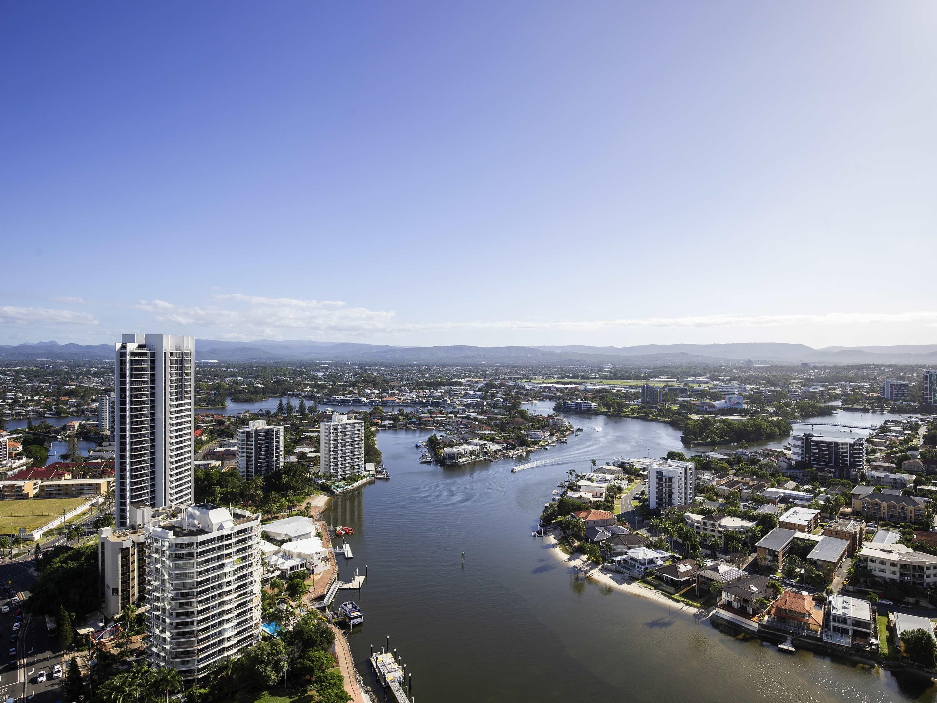 A river running through a city with high-rise buildings on one side and a mix of residential and commercial buildings on the other.
