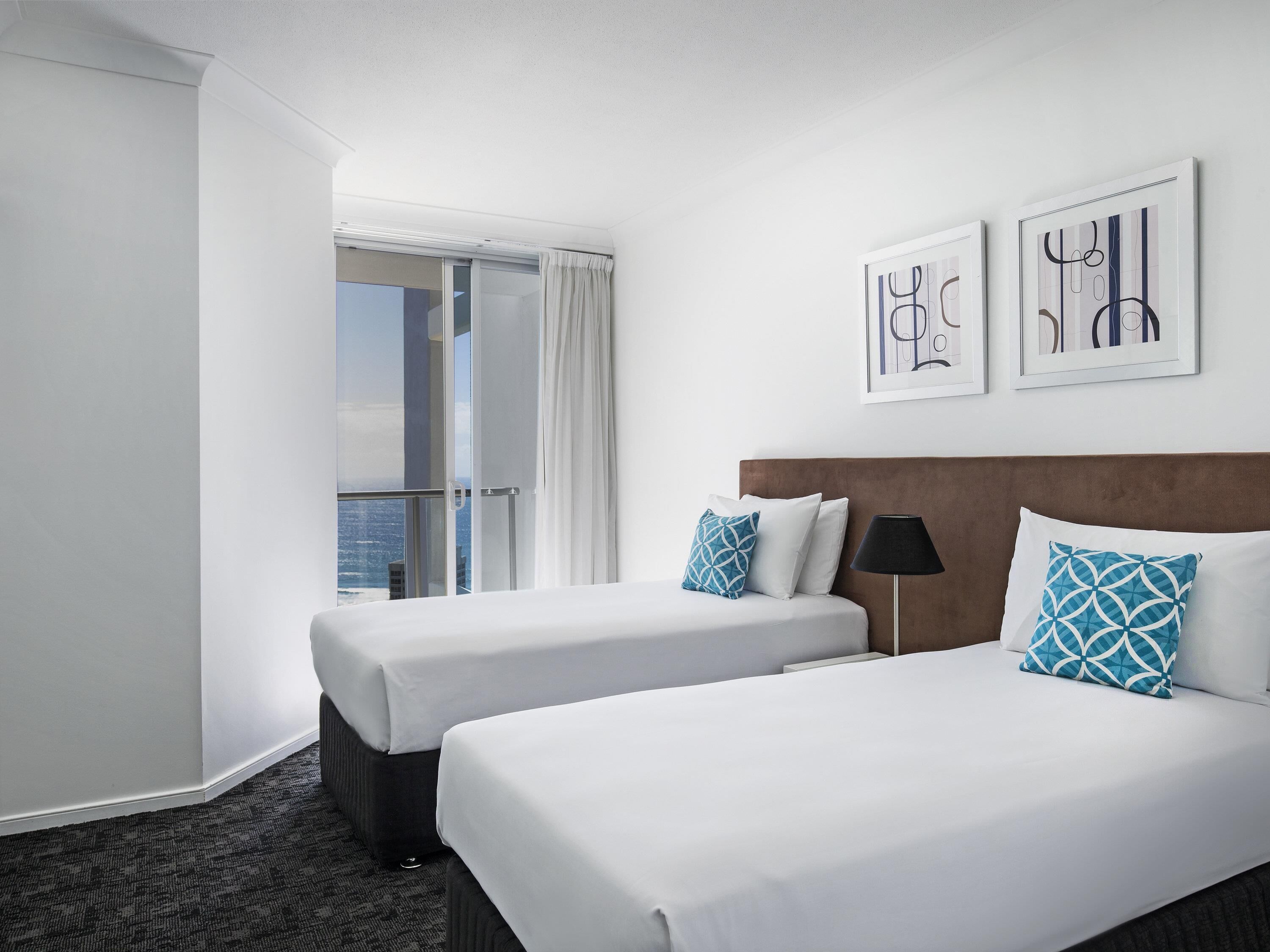 Habitación de hotel con dos camas, vista a la ciudad y obras de arte en la pared.