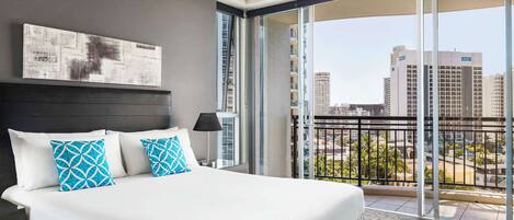 Una habitación de hotel moderna con una cama grande, un balcón con vistas a la ciudad y un cuadro en la pared.