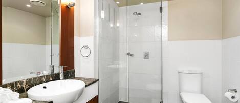 Un baño moderno con ducha envuelta en vidrio, un lavabo blanco y un inodoro.