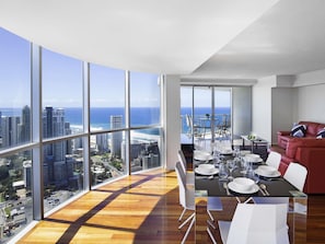Apartamento alto com área de jantar, sofá vermelho e vista para a cidade e oceano.