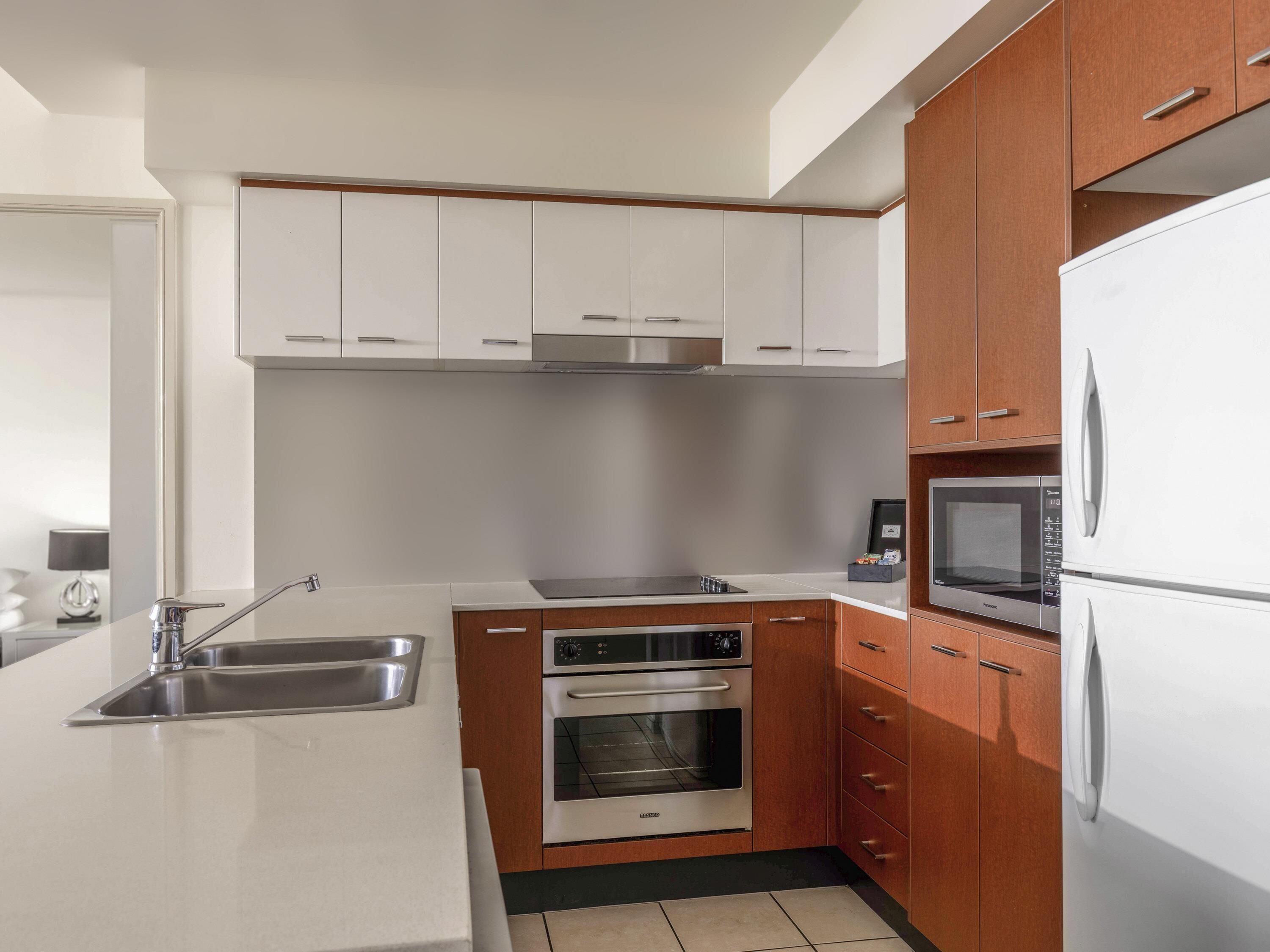 Una cocina moderna con gabinetes blancos, electrodomésticos de acero inoxidable y un horno empotrado.