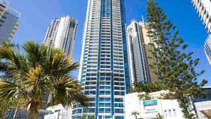 A tall hotel with multiple floors, surrounded by palm trees and other buildings. - Mantra Towers of Chevron (Surfers Paradise)