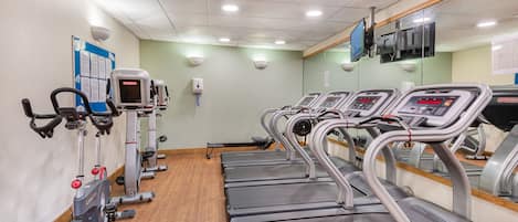Un gimnasio con cintas de correr, bicicletas estáticas y elípticas.