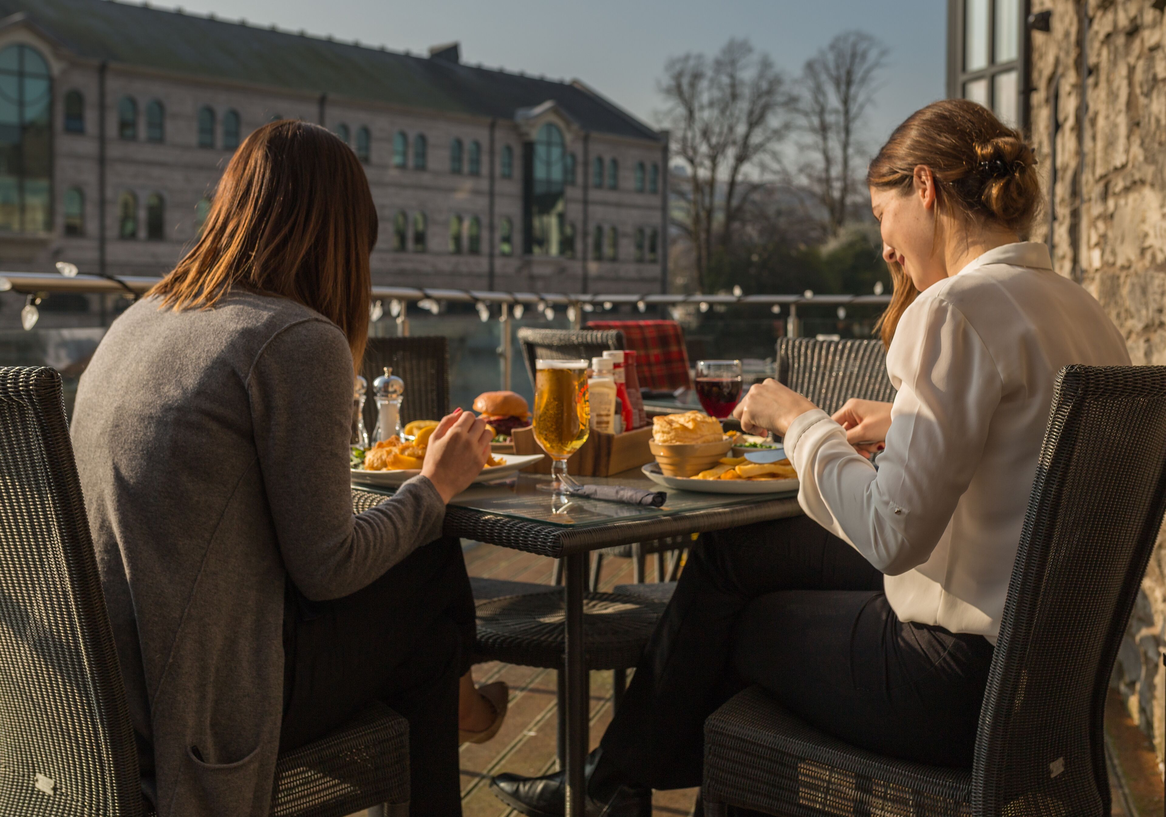 Two people dining at an outdoor table with a view of a historic building in the background.