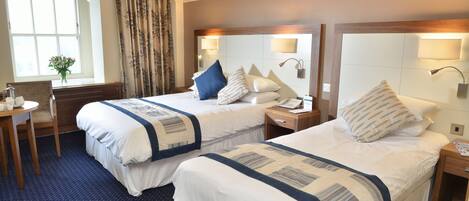 A hotel room with two beds, a desk, and a chair.