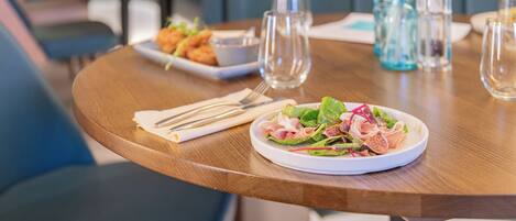 A dining table with a plate of food, a glass of water, and a vase with dried plants.