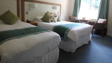 A hotel room with two beds, a desk, and a chair.