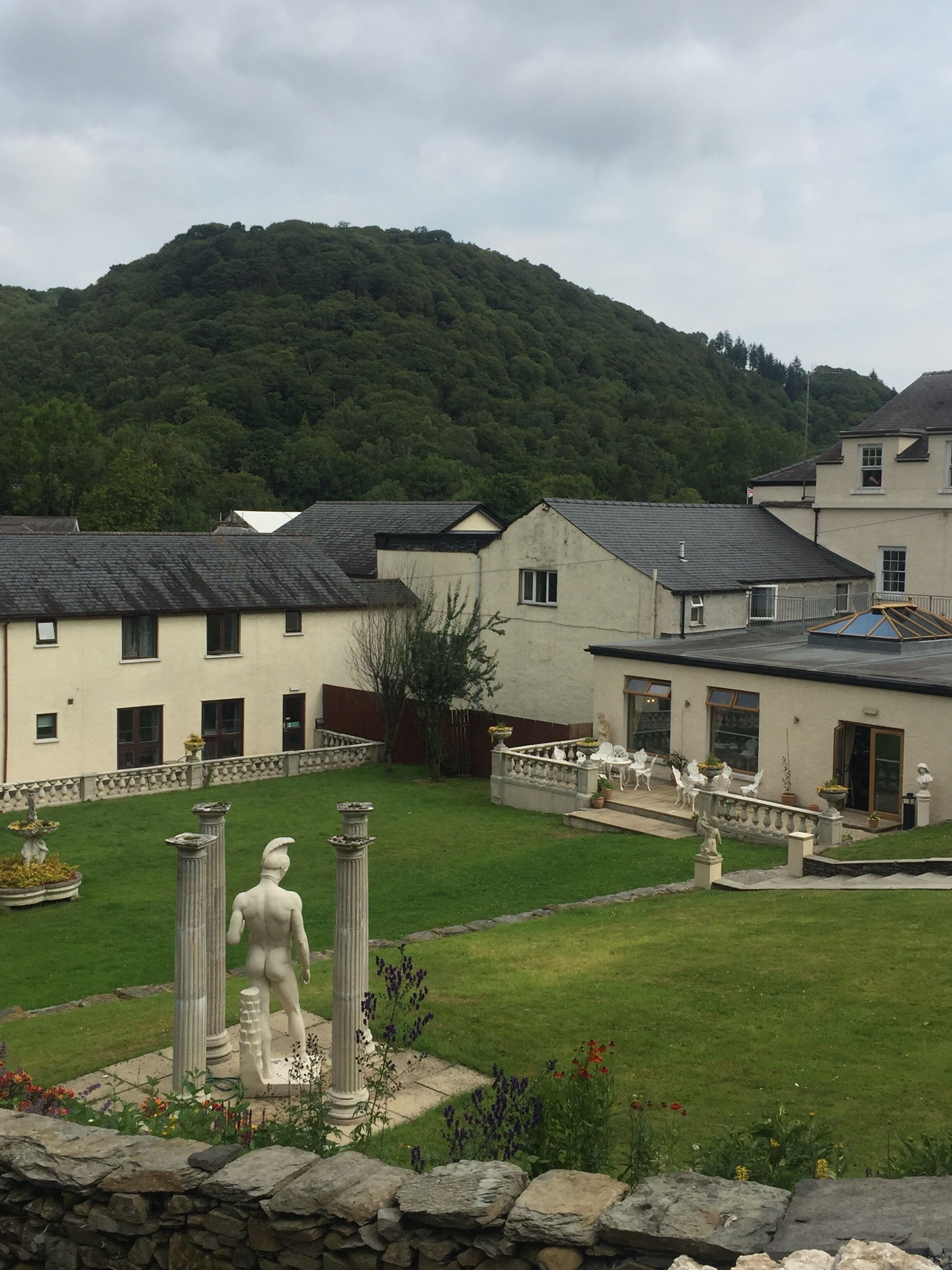 A courtyard with a statue, stone columns, and a mountain in the background.