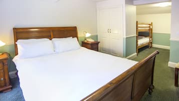 Un dormitorio con una cama de madera grande, una mesita de noche con lámpara, un armario y un espejo.