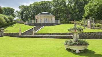 A landscaped garden with a central gazebo, stone steps, and a fountain.