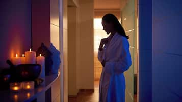 Experience relaxation in a serene, intimate space designed for self-care, featuring a bathtub and candles.
