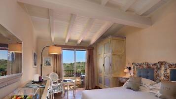 Une chambre d’hôtel comprenant un lit, un bureau avec un plateau de fruits, une chaise, un balcon avec une table et des chaises, et une vue sur l’extérieur.