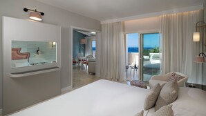 A modern hotel room with a large bed, a sitting area with a view of the sea, and a dining area. - CPH - Pevero Hotel (Arzachena)