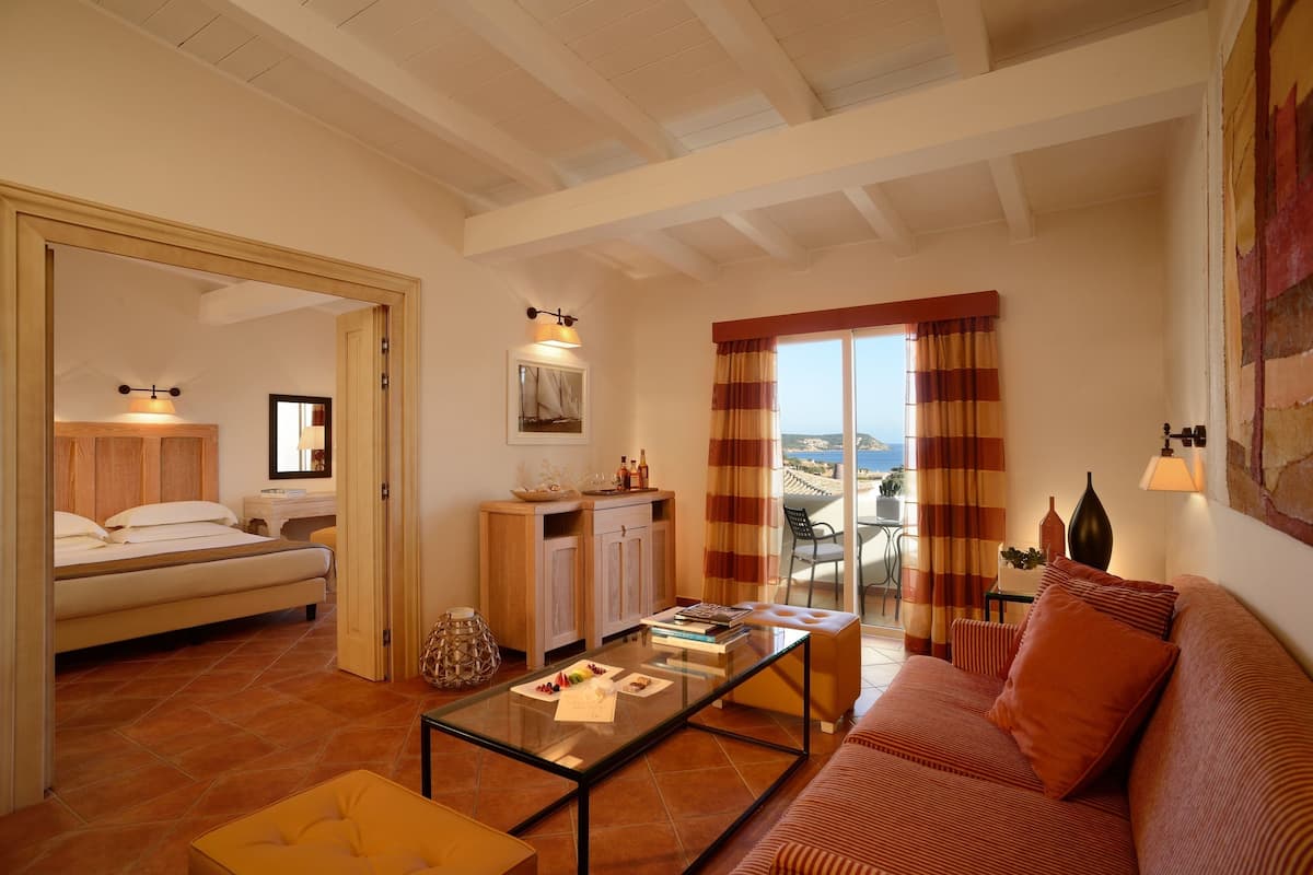 A spacious living room with a sofa, a glass coffee table, and a view of the sea through large windows.