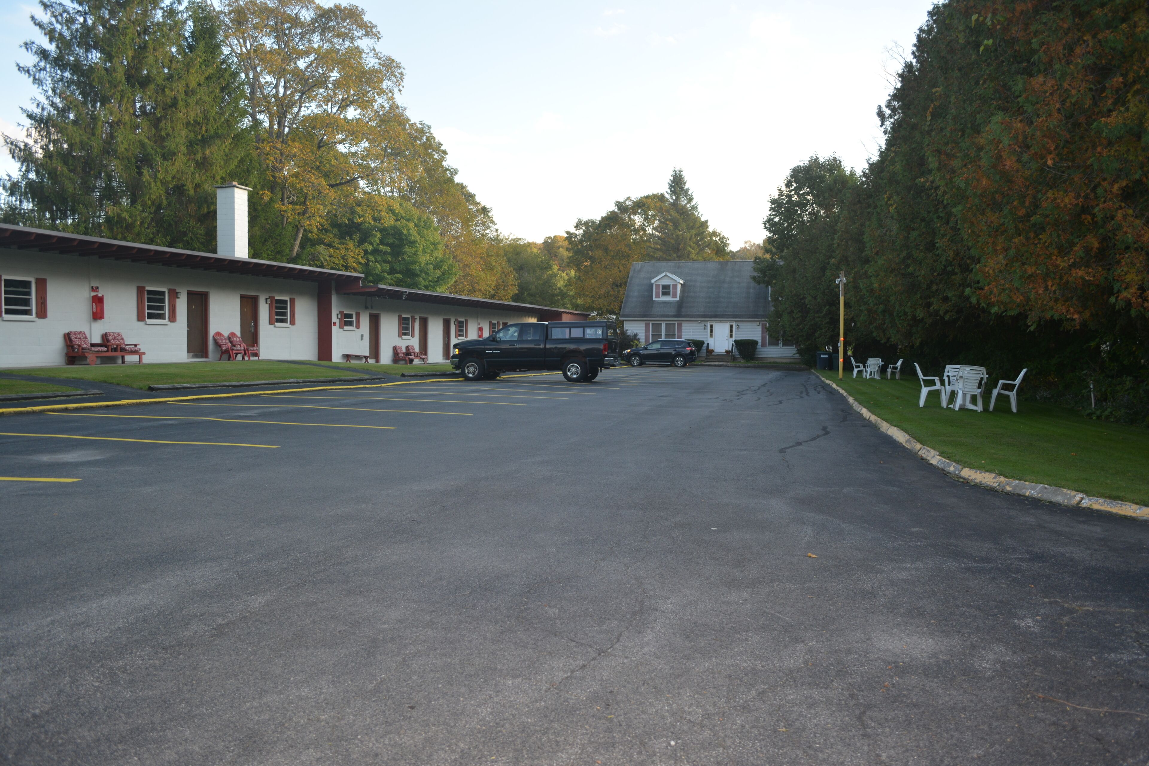 A motel with a parking lot, a black SUV, and a two-story building with a gabled roof.