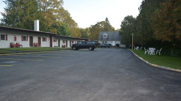 A motel with a parking lot, a black SUV, and a two-story building with a gabled roof.